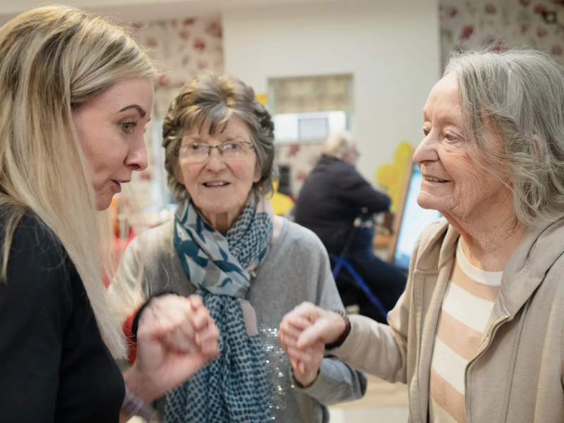 Une intervenante échange avec le sourire avec deux dames âgées.